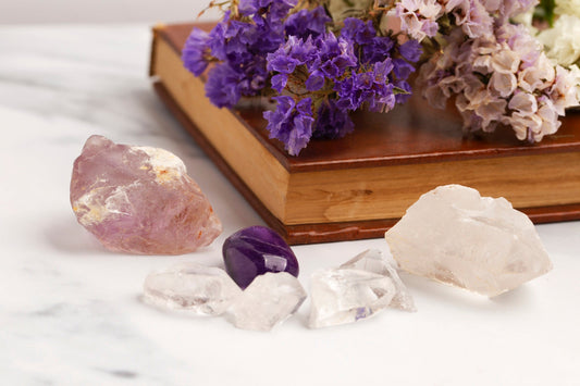 Un bodegón de cartas de tarot y cristales naturales (como grupos de amatista y cristales blancos) colocados armoniosamente sobre un fondo suave y brillante, que sugiere el flujo y la guía de la energía.